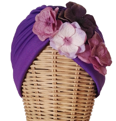 Turbante Primavera malva. Turbante de tela elástica plisada en color malva morado con hortensias en diferentes tonos de morado a un lateral. : PVP 35 euros